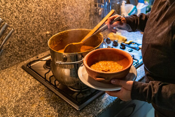 woman serving locro, typical Argentine food on handmade ceramic plates.