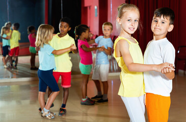 Group of happy cheerful positive smiling childrens trying dancing with partner in classroom