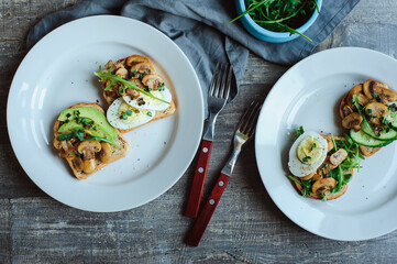 various morning vegetarian toast set with mushrooms, avocado, arugula, cucumber, micro green and eggs. Healthy food on rustic wooden background