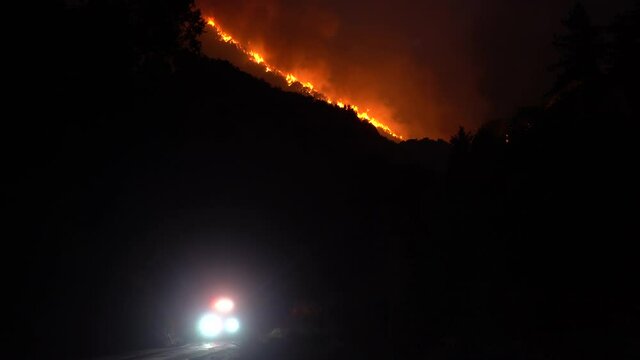 large wildfire with fire engine leaving the scene