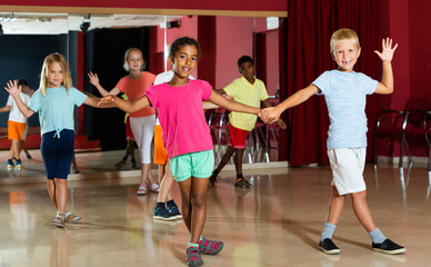 Glad children trying dancing partner dance in modern studio