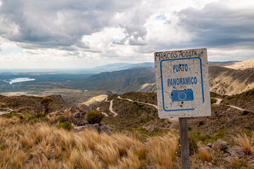 Rusty sign of viewpoint in Gold's Road, San Luis, Argentina, which climbs steppe mountains with curved ascending ways