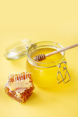 Jar of honey with honeycombs and wooden stick