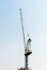 Industrial construction cranes at construction site with clear sky background
