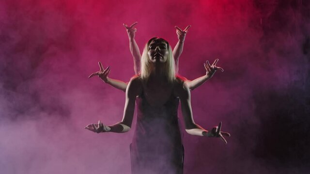 A group of womans in long dresses dance modern choreography in a smoky backlit studio. Slow motion. Close up.