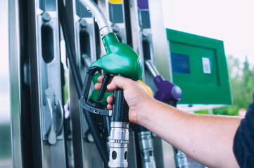 Man holds a refueling gun in his hand for refueling cars. Gas station with diesel and gasoline fuel close-up.