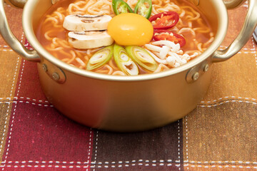 Serving a Korean style instant noodle, Ramyeon with egg yolk, chilli in a traditional korean noodle pot