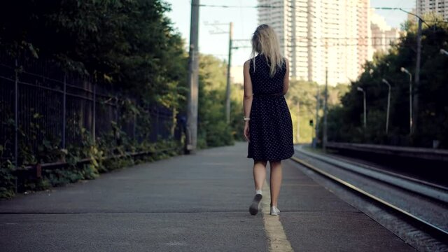 Woman In Dot Dress Walking On Railroad Station Platform.Girl Waiting Train On Public Transport Railroad Station.Female Legs Walking On Summer City.Active Lifestyle On Vacation Travel Tourism Adventure