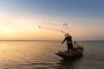 Asian fisherman with his wooden boat in nature river at the early morning before sunrise