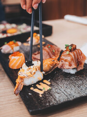 Shrimp sushi nigiri on a black plate with black chopsticks. Closeup of Japanese sushi set nigiri and sushi rolls.Eating japanese food on black slate dishes at restaurant