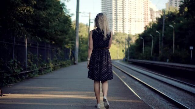 Woman In Dot Dress Walking On Railroad Station Platform.Girl Waiting Train On Public Transport Railroad Station.Female Legs Walking On Summer City.Active Lifestyle On Vacation Travel Tourism Adventure