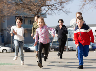 Kids spending time together outdoors running on square at warm spring day