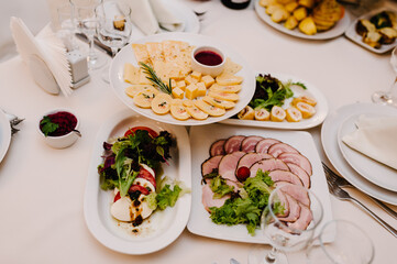 Serves dinner on a festive table. Food, Salads, Meat, Fish Meals. Festive table at wedding banquet. Decor. Details.