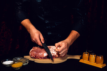 The cook cuts the fat on the neck, prepares the meat for marinating and roasting.