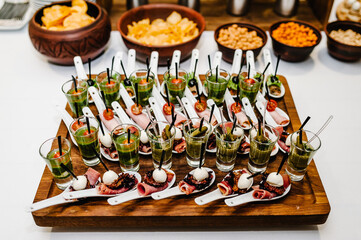 Plate on the table with gourmet variety of mini appetizers with different toppings. Assorted Italian appetizer on plastic spoons.