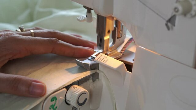 Asian Seamstress hands working Overlock machine.