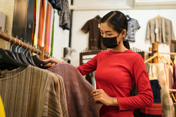 Young travel woman chooses Thai traditional dressing in Village shop, Thailand handmade product.
