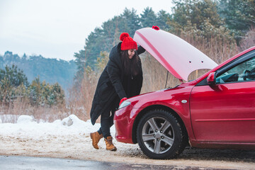 woman looking at engine broken car at winter road side