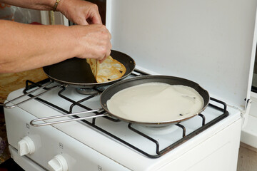     Cooking pancakes in two pans on a gas stove.