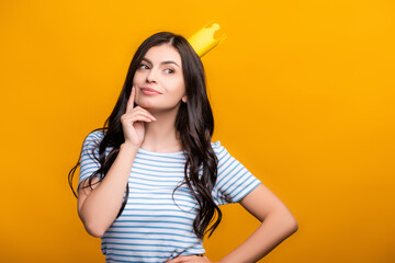 pensive brunette woman in paper crown looking away isolated on yellow