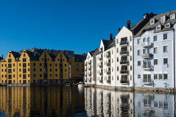 Fototapeta na wymiar Beautiful old stone houses with art nouveau facades directly on the waterfront in Ålesund on a clear sunny winter day