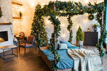 comfort, interior and holidays concept - cozy bedroom christmas tree and garland