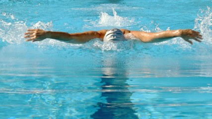 Shot from the Front Side of a Professional swimmer is swimming butterfly in a pool. Butterfly technique. Butterfly training.