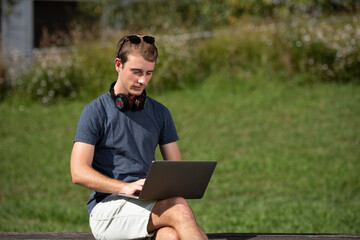 Handsome young  blond man working on his computer outdoors