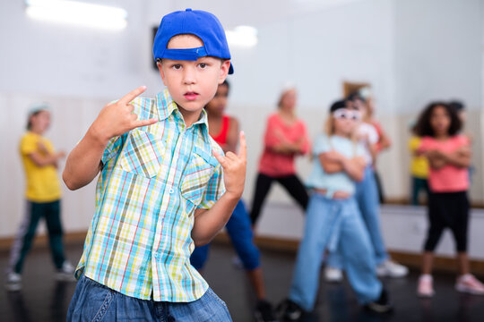 Preteen boy in cap performing hip-hop at group dance class