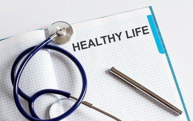 Paper with text HEALTHY LIFE on table with stethoscope