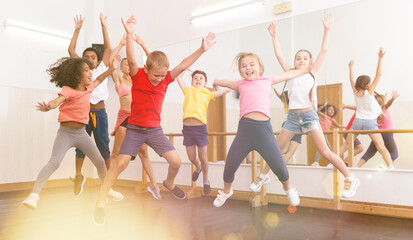 Group of cheerful children dancing and jumping in dance studio during class