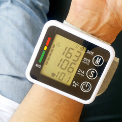 Measure your blood pressure at home using a portable device to check Your health. The device shows a high pressure value.