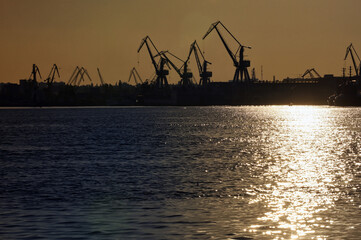 Obraz premium Harbor and Cranes against red sunset background
