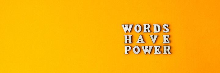 Quote WORDS HAVE POWER made out of wooden letters on bright yellow background.