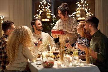 holidays, celebration and people concept - happy smiling friends having christmas dinner at home in...
