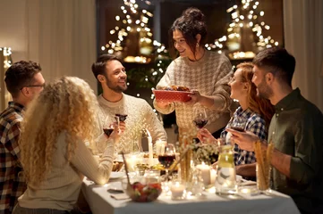 Fotobehang Kruidenier holidays, celebration and people concept - happy smiling friends having christmas dinner at home in evening  © Syda Productions