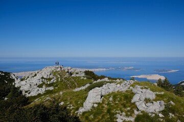 Velebit National Park, Dinaric Mountains, Croatia - circa July 2020: The beautiful Premuziceva Staza mountain path overlooking the Adriatic Sea and islands. Silhouettes of people on viewpoint.