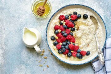 Oatmeal porridge with fresh berries and honey for a breakfast, Top view with copy space.