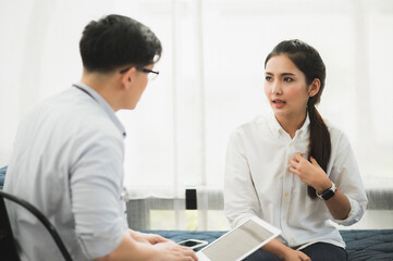 Young handsome asian psychologist doctor using laptop consulting to female patients in therapy session.