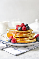 Hot banana pancakes with fresh berries and honey for a breakfast.