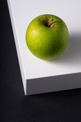 selective focus, green fresh Apple on a white cube, on a black background