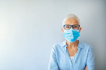 Closeup up portrait of adult woman wearing medical mask indoors. Looking at camera. Virus concept. Portrait of woman wearing face mask during Covid-19 pandemic outbreak
