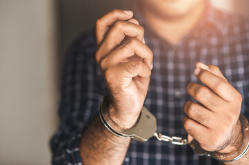 Prisoner man in jail with handcuffs. Close up Shackled in Hands.
