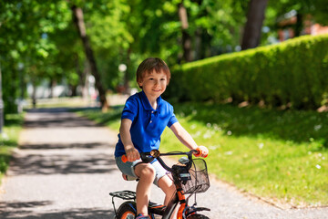 Fototapeta na wymiar childhood, leisure and people - happy smiling little boy riding bicycle at summer park