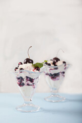 Dessert of cream, currants and cherries, decorated with mint leaves on a white plate. Copy spaes. vertically
