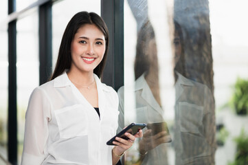 Beautiful asian woman using smartphone. Smiling charming happy young female with cellphone stay at home.