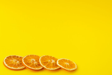 Dehydrated dried orange slices on a bright yellow background. Beautiful background for text, copy space. The concept of aromatherapy and healthy food, vitamins