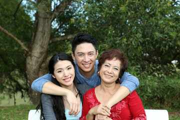 Naklejka premium Southeast Asian family adult senior parents mother son daughter sit on park bench happy at outdoor park