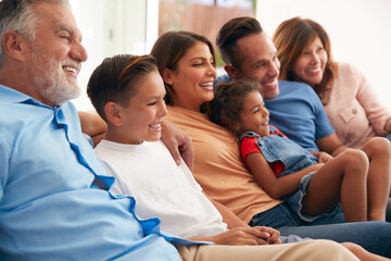 Fototapeta na wymiar Multi-Generation Hispanic Family Relaxing At Home Sitting On Sofa Watching TV Together