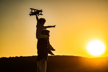 Fototapeta na wymiar Sunset silhouette of child and dad playing. Kid pilot aviator and daddy dreams of traveling. Happy boy child.